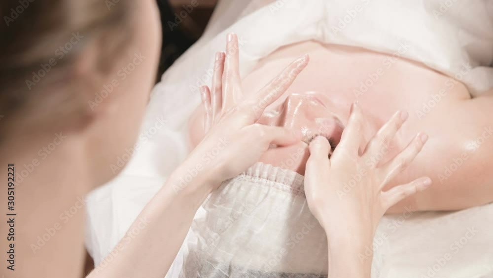 Close-up Spa facial Massage. Girl professional massage therapist does a relaxing facial massage to an attractive client of a spa salon