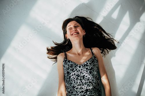 Fotografie carefree brunette woman lying on the floor laughing