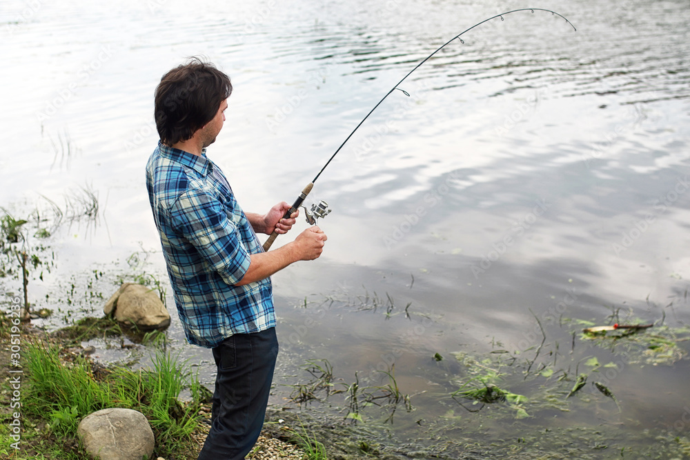 A man with a beard is fishing in the river A man with a beard is fishing in the river