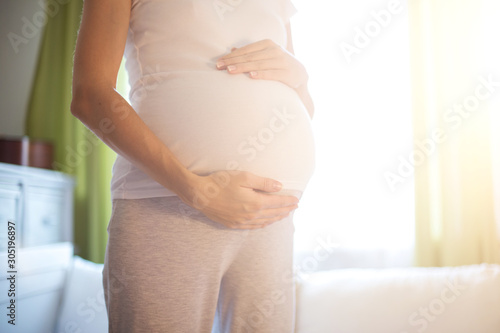 Pregnant woman standing near window at home