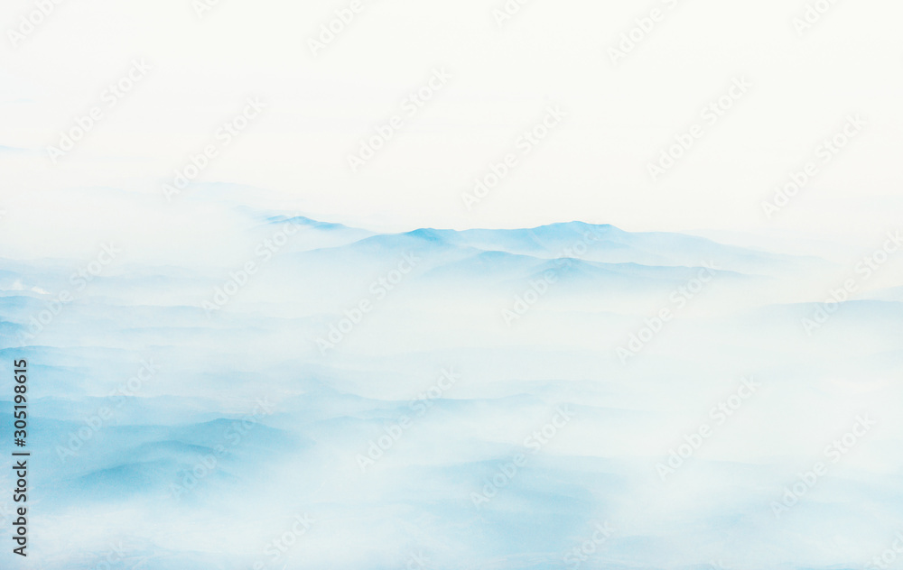 Aerial view of distant mountains layers range in morning mist. Meditation and zen landscape.