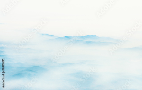 Aerial view of distant mountains layers range in morning mist. Meditation and zen landscape.