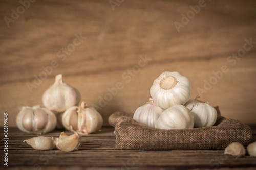 Garlic cloves and bulb in cloth vintage. Garlic cloves on rustic table in wooden bowl. Fresh peeled garlic and bulbs.