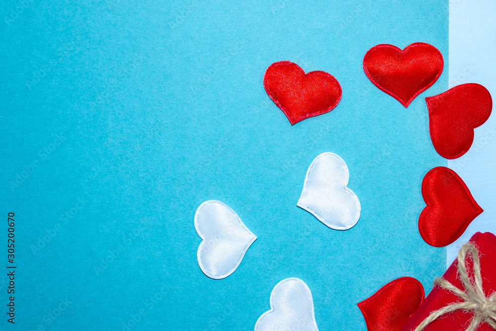 Background for Valentine's Day with red and white hearts and a gift. Hearts on a blue background. Horizontal top view, flat lay. Background for Valentine's Day with red and white hearts and a gift. Hearts on a blue background. Horizontal top view, flat lay.
