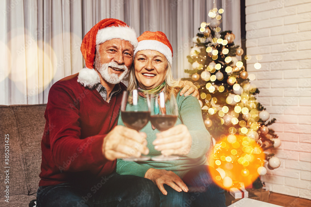 Happy and funny senior couple drinking wine and celebrating New Year in their home.