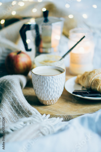 Cozy winter weekend breakfast, coffee and croissant on wooden tray photo