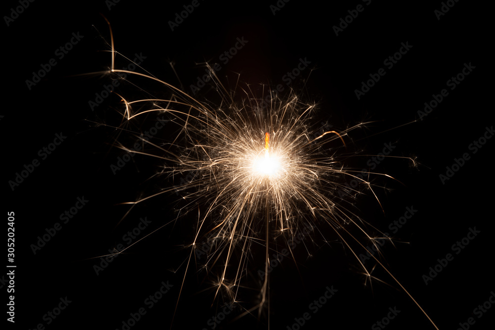 Burning sparkler on black background