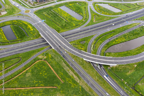 Obraz na płótnie A cloverleaf highway with traffic in the middle of green fields near Waalwijk, B