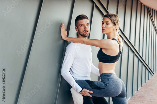 Beautiful fitness sport girl together with sportmen with fit body in sportswear exercising outdoors, stretching, yoga, outdoor sports, urban style. Sportment holding a sportgirl.