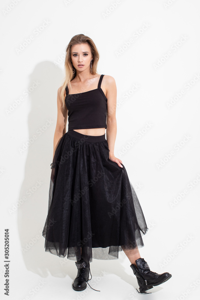 Girl in t-shirt and black skirt posing on a white background. Fashion shooting