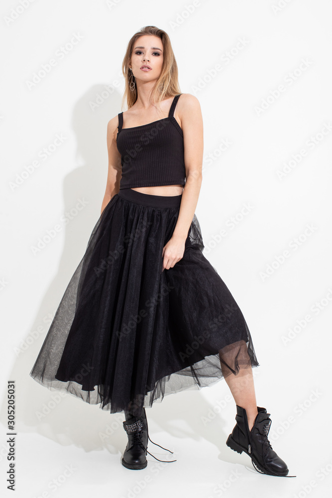 Girl in t-shirt and black skirt posing on a white background. Fashion shooting Girl in t-shirt and black skirt posing on a white background. Fashion shooting