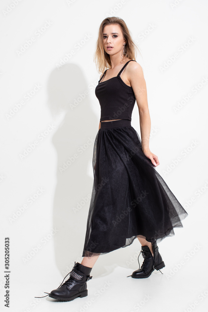 Girl in t-shirt and black skirt posing on a white background. Fashion shooting Girl in t-shirt and black skirt posing on a white background. Fashion shooting