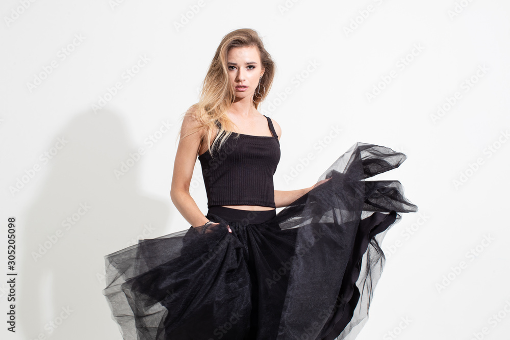 Girl in t-shirt and black skirt posing on a white background. Fashion shooting