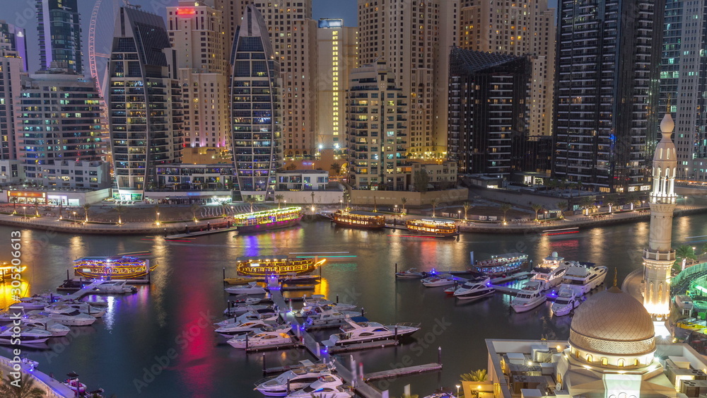 Yachts in Dubai Marina flanked by the Al Rahim Mosque and residential towers and skyscrapers aerial day to night timelapse. Yachts in Dubai Marina flanked by the Al Rahim Mosque and residential towers and skyscrapers aerial day to night timelapse.