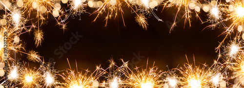 Silvester background banner panorama long- sparklers and bokeh lights on black texture, top view with space for text