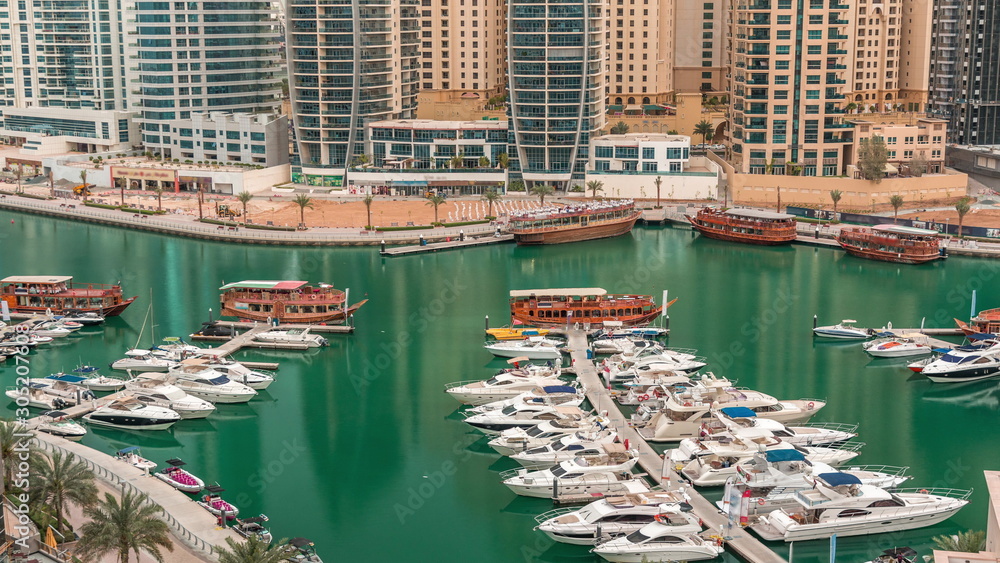 Luxury yachts parked on the pier in Dubai Marina bay with city aerial view timelapse