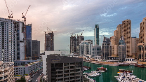 Luxury yachts parked on the pier in Dubai Marina bay with city aerial view timelapse