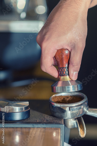 Pressing ground coffee tamper making espresso closeup.