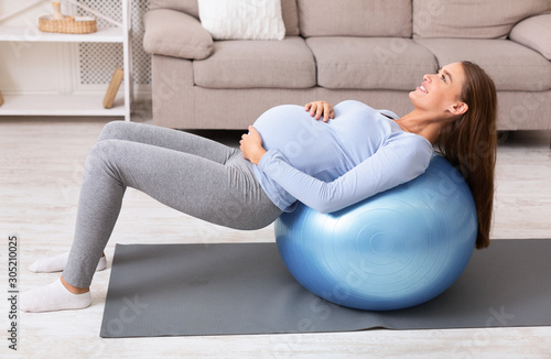 Pregnant girl working out with fitness ball at home