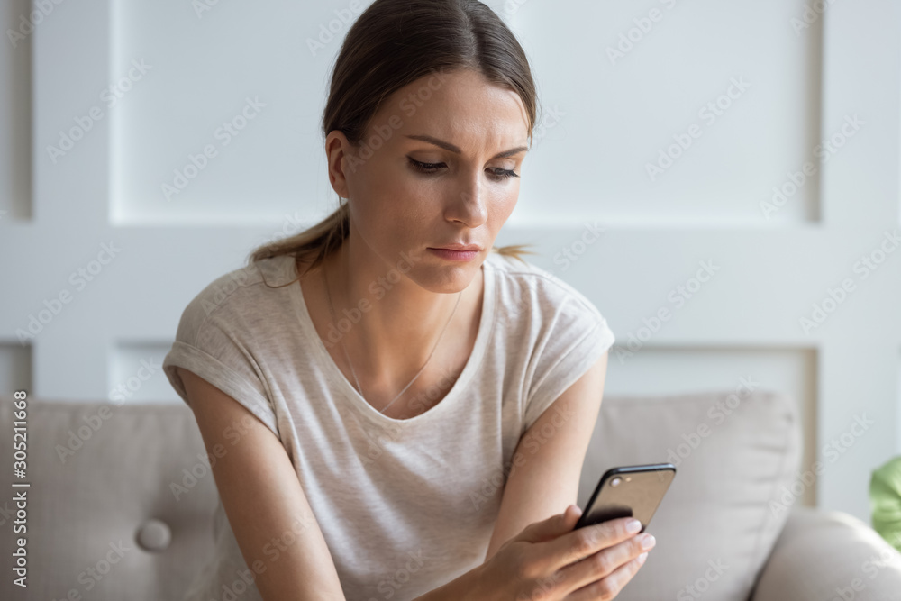 Thoughtful young woman looking at cellphone screen. Thoughtful young woman looking at cellphone screen.