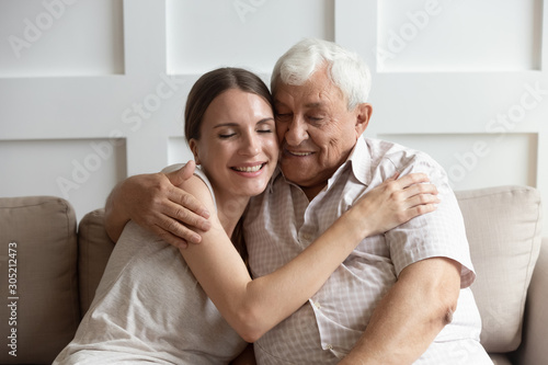 Caring adult young woman cuddling happy older hoary father.