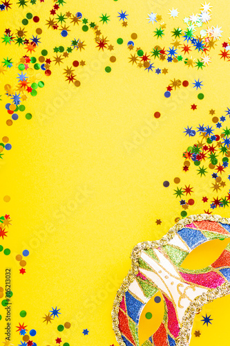 Festive yellow background with colorful carnival mask. Greeting card concept voor birthday, carnival, party. Copy space, top view, flat lay.