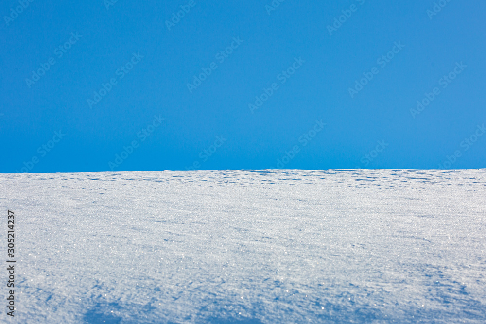 Snow drift patterns on background of blue sky.