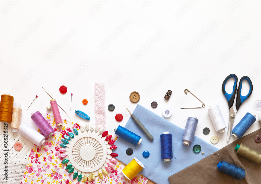 Sewing accessories: threads, fabrics, scissors, buttons, needles, pins and  other sewing tools on a white background. Top view, copy space, flat lay,  mock up. Stock Photo