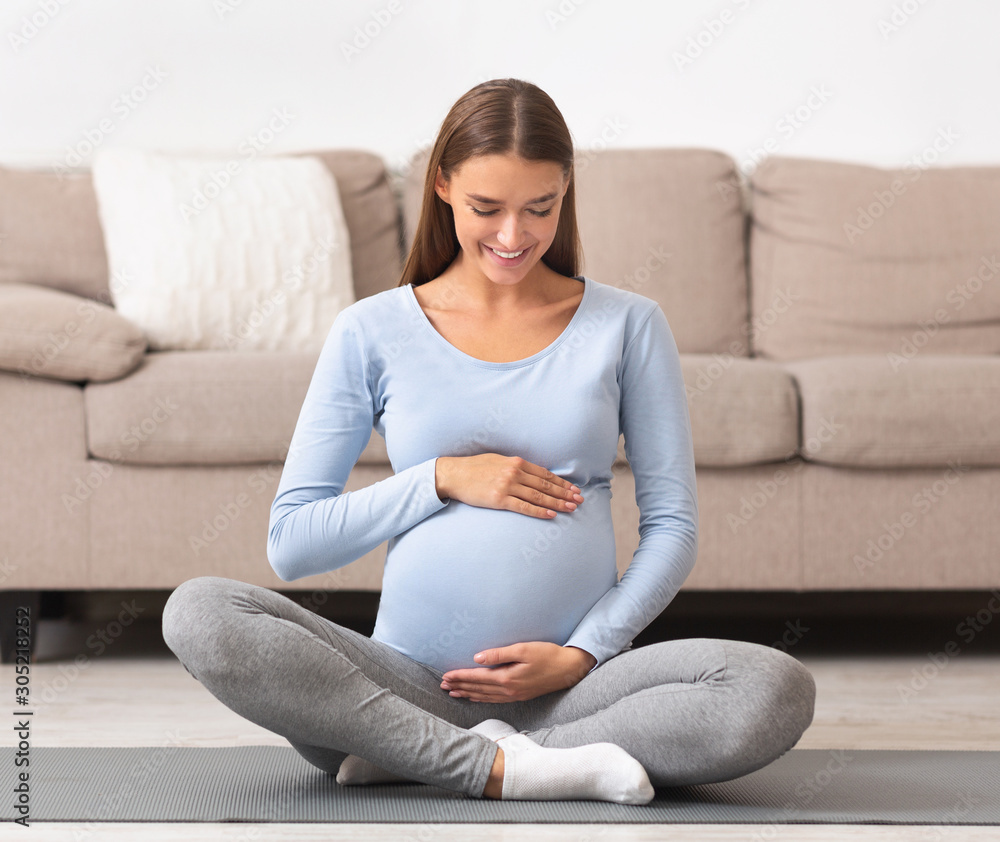 Attractive pregnant woman touching her belly and smiling