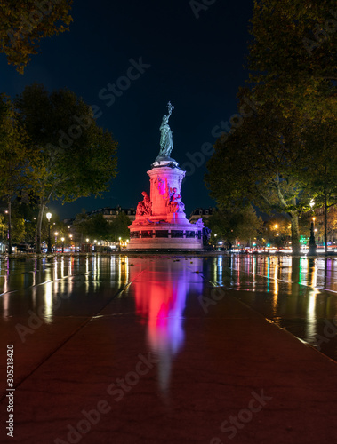 Paris by night the monument to the Republic with the symbolic statue of Marianna, in Place de la Republique water reflection red color