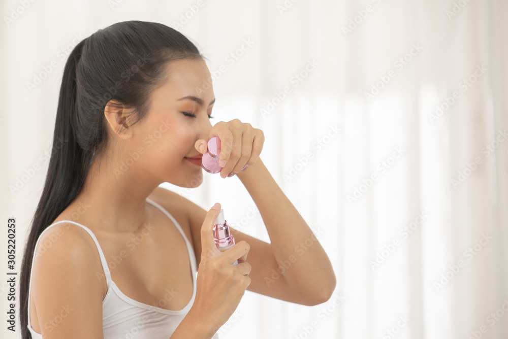Young Woman Smelling At Beauty Product While Sitting On Bed At Home Young Woman Smelling At Beauty Product While Sitting On Bed At Home