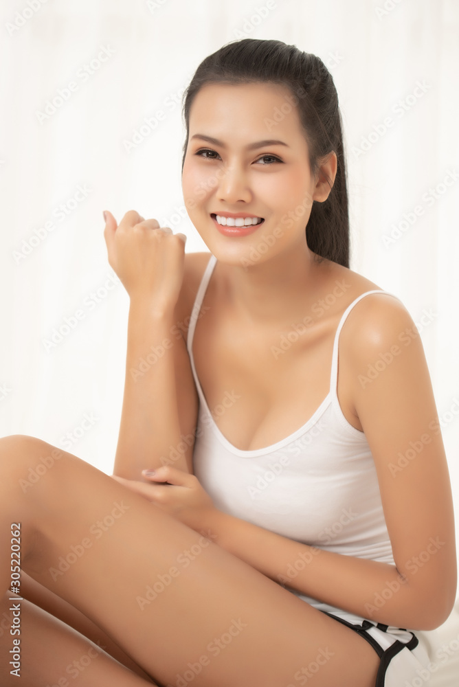 Young Woman Applying Beauty Product While Sitting On Bed At Home Young Woman Applying Beauty Product While Sitting On Bed At Home