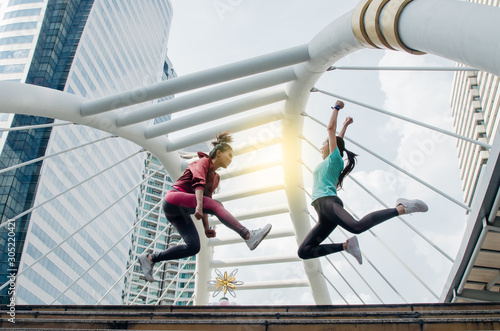 Low Angle View Of Women With Arms Raised Jumping Against Sky