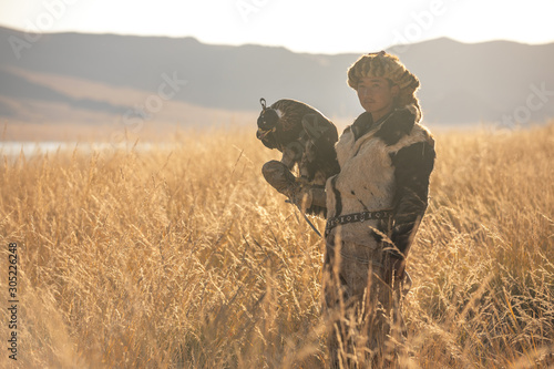 Portrait of a young kazakh eagle hunter with his majestic golden eagle in the steppe. Ulgii, Mongolia.
