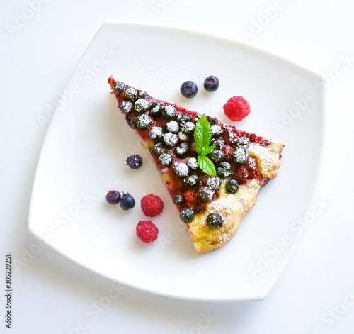 A piece of berry pie and fresh berries on a plate top view isolated
