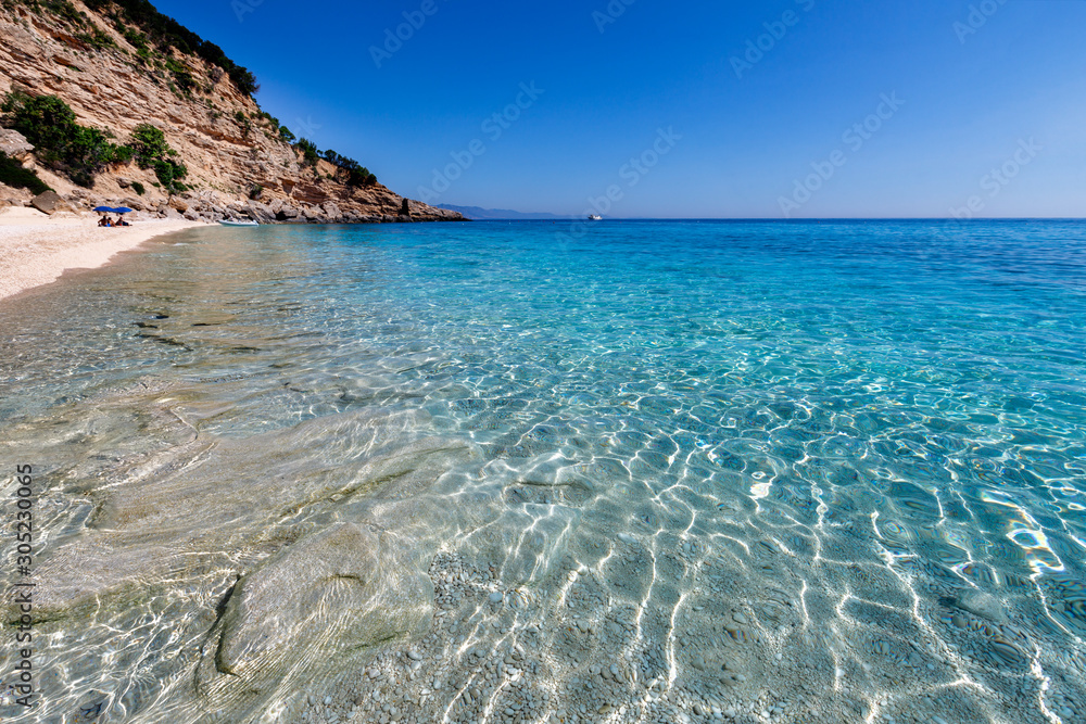 Crystal clear azure water of the natural beach near Cala Biriola, Sardinia island, Italy. Blue sky, calm and tranquility. Holidays in Sardinia.