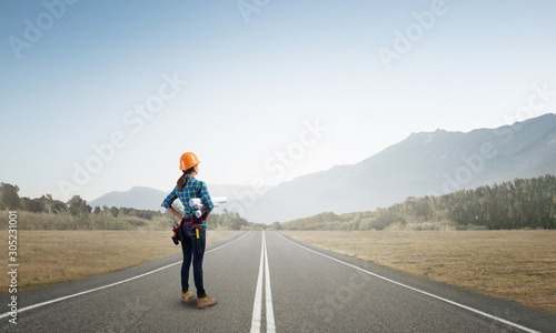 Young woman in safety helmet standing on road © adam121