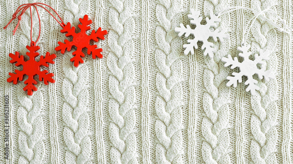 Red and white snowflakes on the white knitted background. New Year, Christmas and winter concept Red and white snowflakes on the white knitted background. New Year, Christmas and winter concept