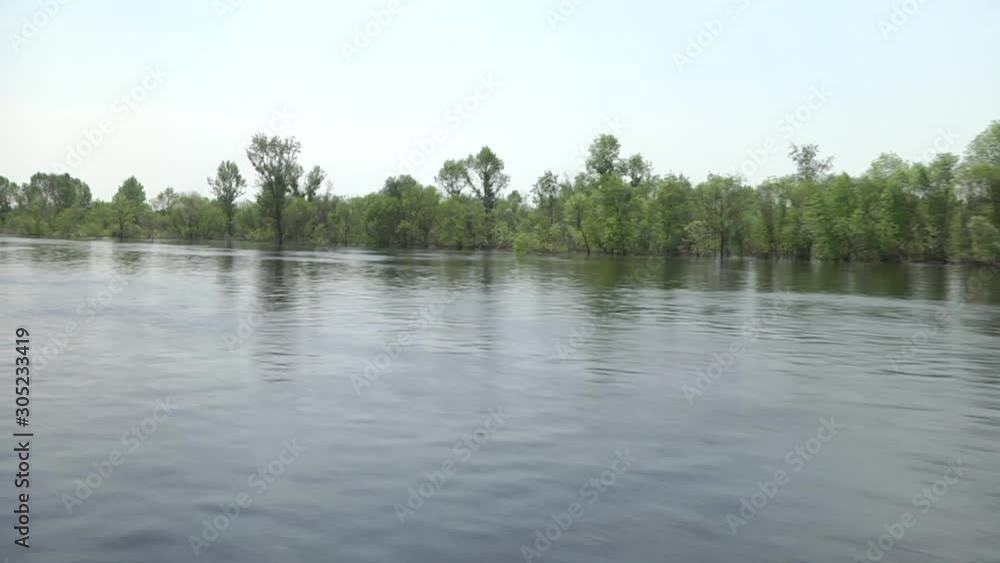 Spring flooding. Overflow of water from the river. Trees stand in the water. A boat ride on the river. Forest river under a blue cloudy sky. Spring flooding. Overflow of water from the river. Trees stand in the water. A boat ride on the river. Forest river under a blue cloudy sky.