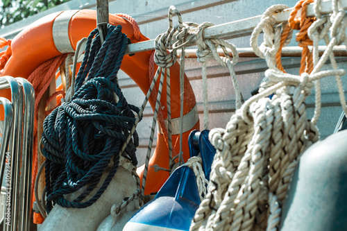 Many tied ropes and a life buoy. Many coiled anchor ropes and ship fenders