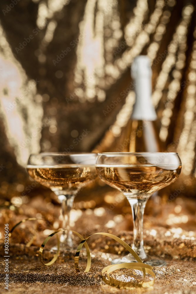 two champagne flute with shiny bottle on golden shiny background