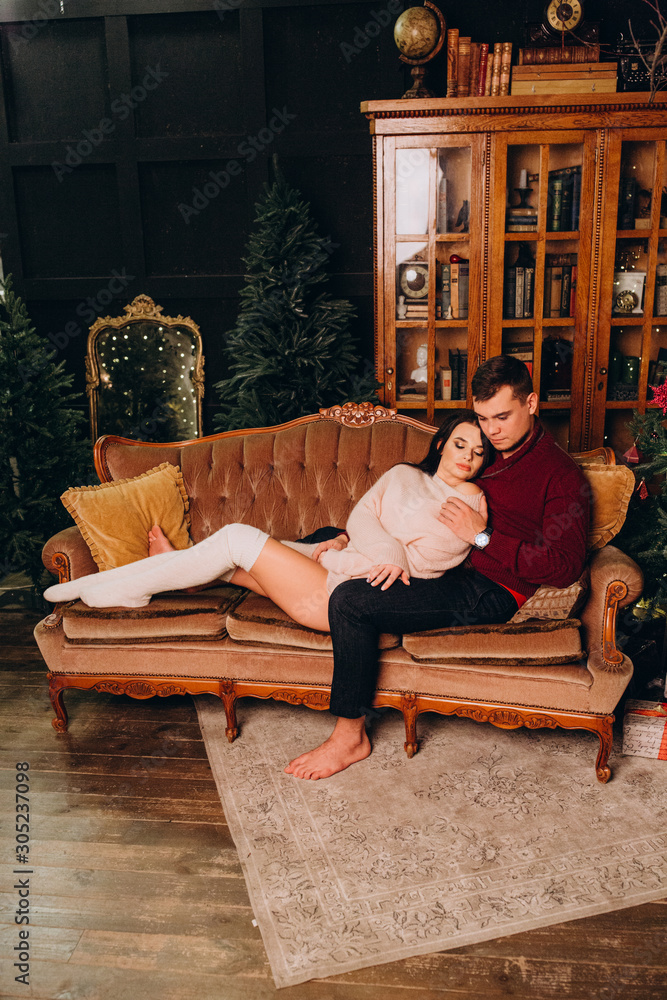 A guy with a girl is celebrating Christmas. A loving couple enjoys each other on New Year's Eve in a cozy home environment. New Year's love story. A guy with a girl is celebrating Christmas. A loving couple enjoys each other on New Year's Eve in a cozy home environment. New Year's love story.