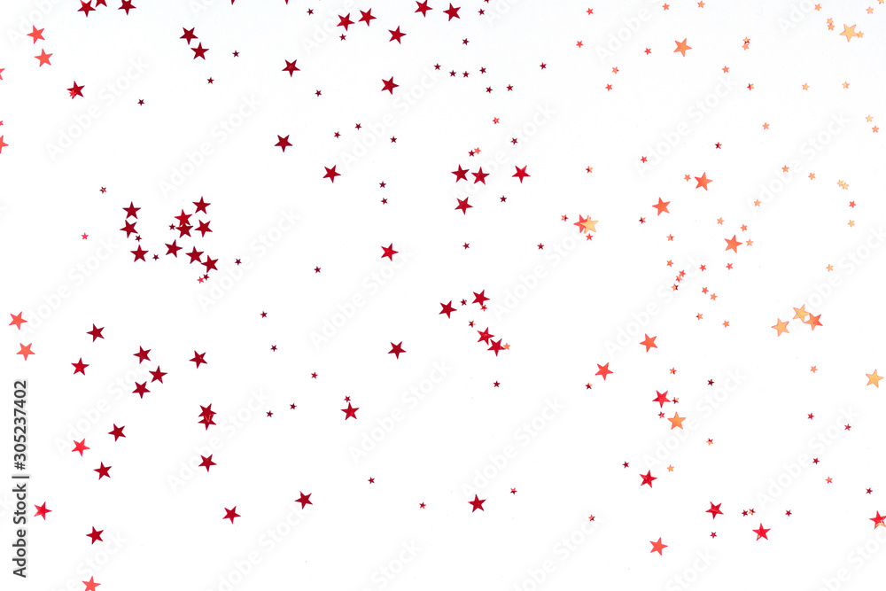 Red stars glitter confetti on white background. Festive backdrop.