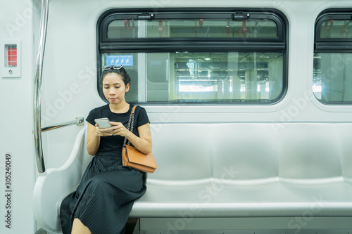 Asian woman using mobile phone in train