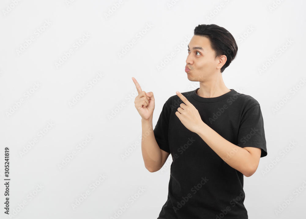 Young asian man with black shirt pointing to the side with a finger to present a product or an idea while looking forward surprising isolated on white background. Young asian man with black shirt pointing to the side with a finger to present a product or an idea while looking forward surprising isolated on white background.