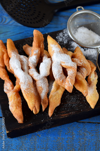 Crunchy brushwood cookies dusted with sugar powder on the blue table photo