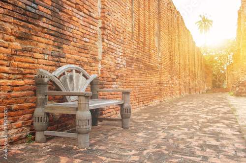 Vintage chair wooden and traditional red brick wall exterior wall with sunshine morning. Surface texture masonry bright cleaned brickwork background.