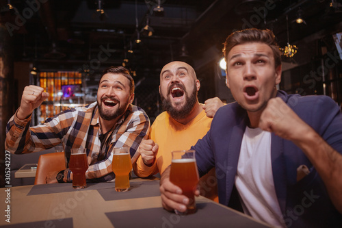 Group of friends scraming, watching football game at beer pub. Male soccer fans looking excited, celebrating victory of their favorite team © mad_production