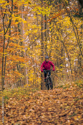 nice senior woman riding her mountainbike on the autumnal forest trails near Stuttgart, beautiful warm colors © Uwe