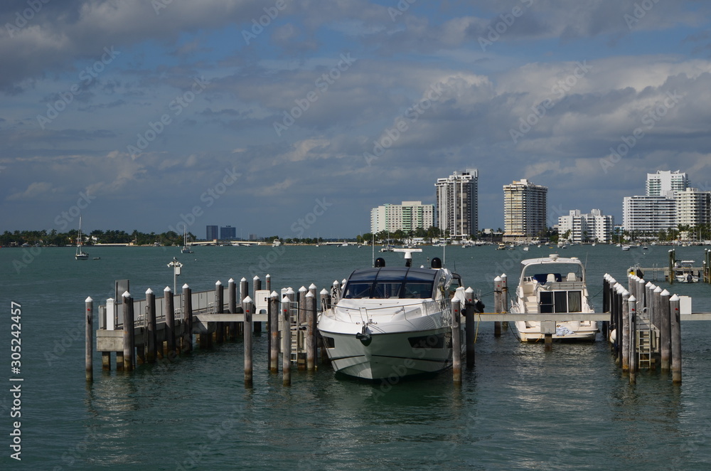 An upscale cabin cruiser docked at a small marina and luxury Miami Beach condos over looking Biscayne bay